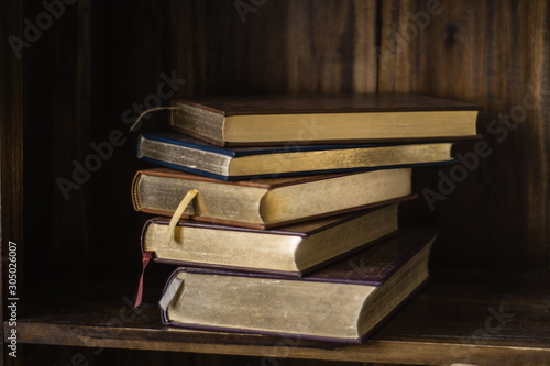 Stack of old dusty books, vintage classic books on the wooden wardrobe