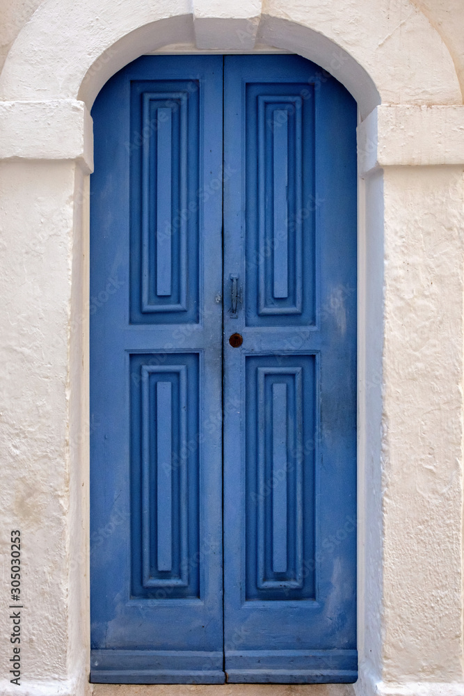 Blue paneled door in a stone arch.