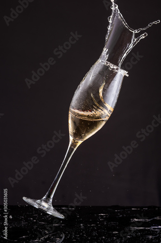 falling glasses with white wine champagne, splash and splatter on a black background