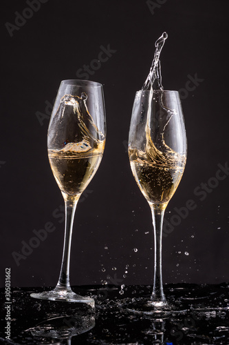 falling glasses with white wine champagne, splash and splatter on a black background