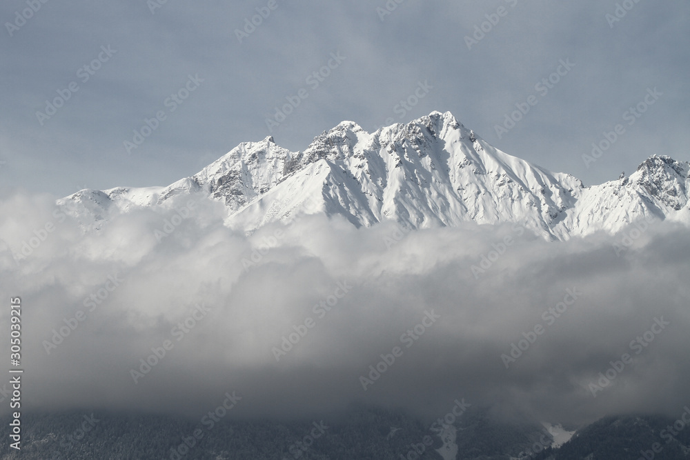 Blick von Innsbruck im Inntal in Tirol auf die Nordkette und die schneebedeckten Gipfel im Winter. Nebeldecke