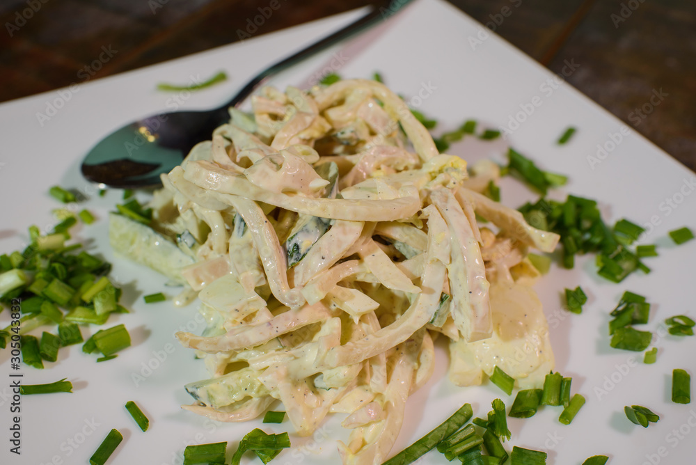 Squid salad on a large white plate on a wooden table Squid salad on a large white plate on a wooden table