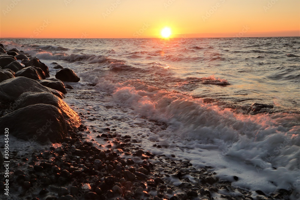 Obraz premium waves with surf foam at the shore line at sunset
