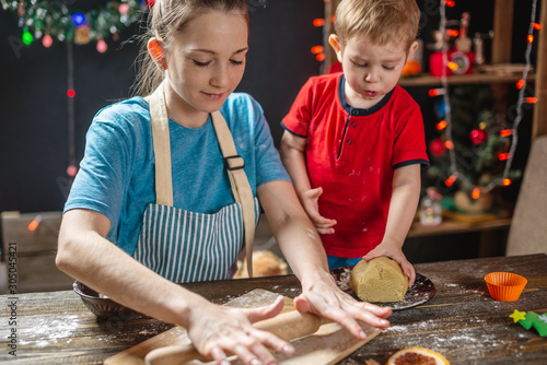 Mom and child son shape the dough for baking homemade holiday cookies. Family cooking in Christmas decorations