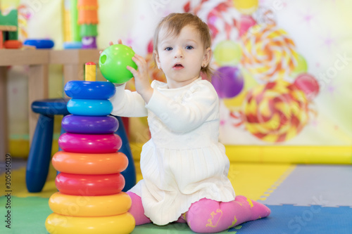 Two-year old  girl playing with wooden blocks  in kindergarten