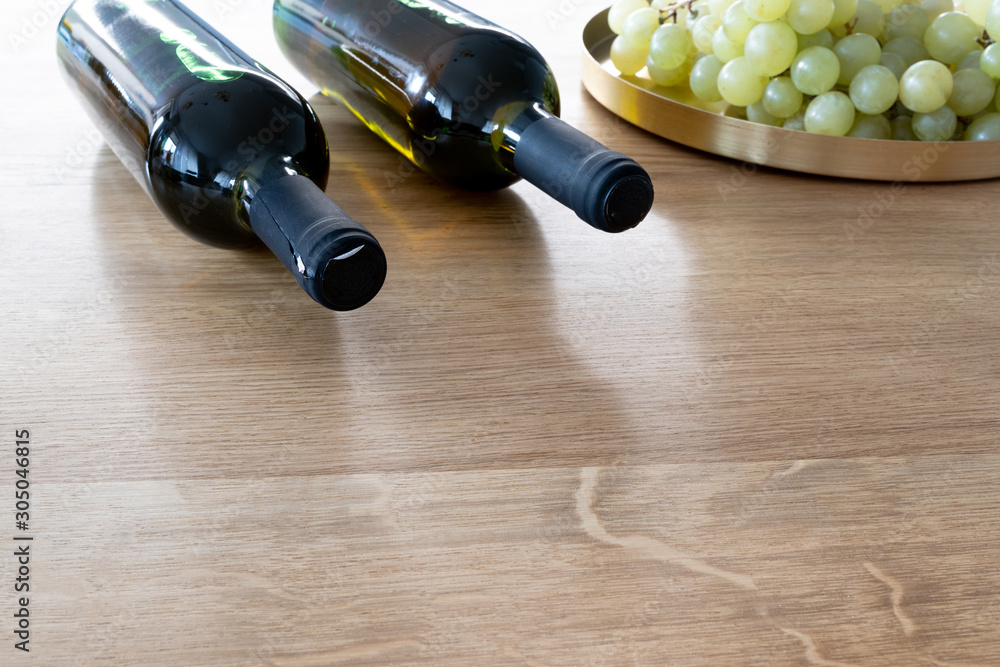 Obraz premium Bunch of grapes and a bottle of organic wine on a wooden table as a background. Front perspective view. Copy space in front of the picture.