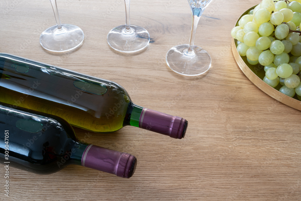 Obraz premium Bunch of grapes and a bottle and wine glasses wine on a wooden table as a background. Front perspective view. It’s party time.