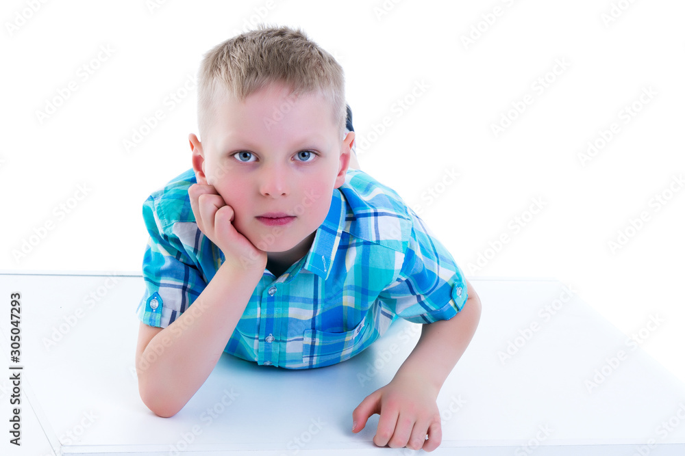 A beautiful little boy is photographed near a white cube. The co A beautiful little boy is photographed near a white cube. The co