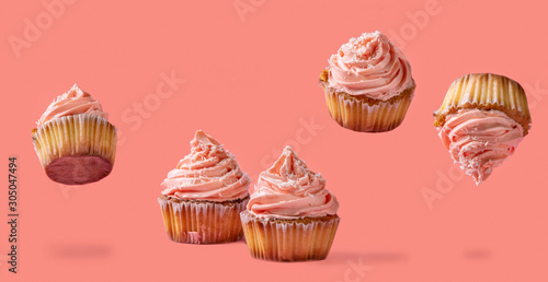 Homemade levitation cupcakes with pink buttercream and coconut flakes over red pink background.