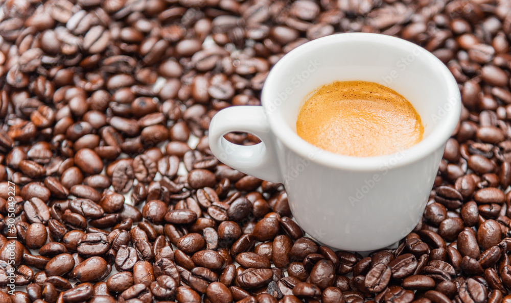 Close up cup of espresso coffee and whole roasted coffee beans, copy space Close up cup of espresso coffee and whole roasted coffee beans, copy space