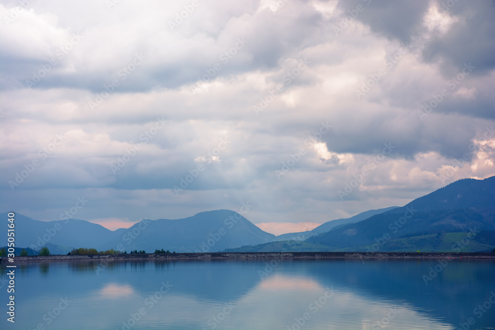 liptovska mara water reservoir in the evening. cloudy springtime weather above the distant mountains reflecting in the calm lake. popular travel destination of slovakia