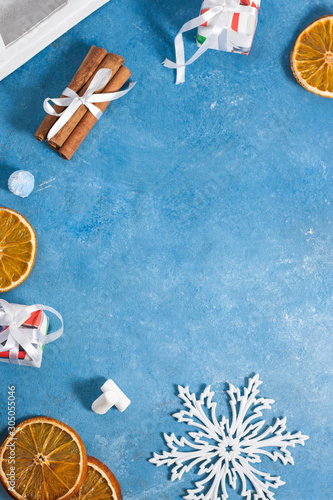 Christmas composition.Frame made of christmas decorations from snowflakes, gifts, cinnamon and orange slices on a blue background. Christmas, winter, new year concept. Flat lay, top view, copy space