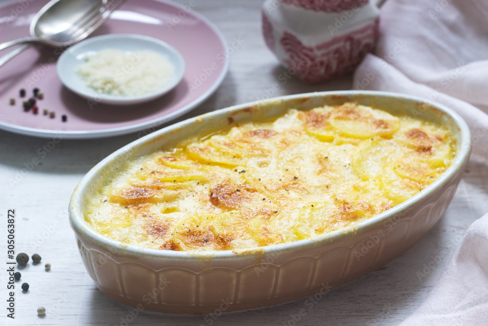 French dish Gratin Dauphinois in ceramic form on a light background. Rustic style. French dish Gratin Dauphinois in ceramic form on a light background. Rustic style.