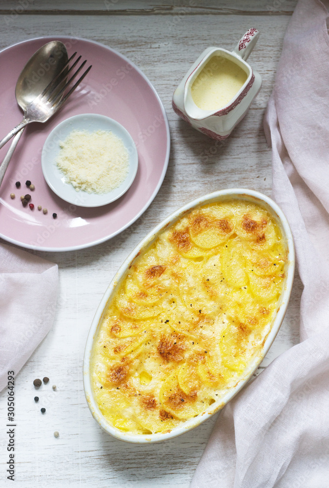 French dish Gratin Dauphinois in ceramic form on a light background. Rustic style. French dish Gratin Dauphinois in ceramic form on a light background. Rustic style.