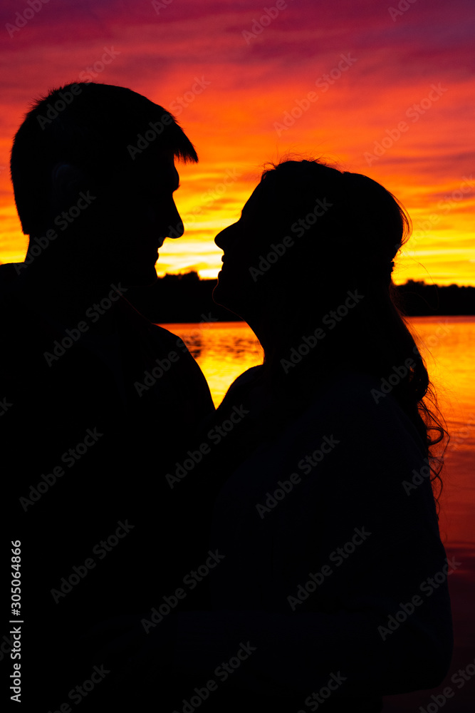 Silhouette of a couple in front of a lake sunset.