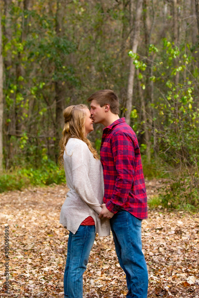 Man kissing his girlfriend on top of the head in the park Man kissing his girlfriend on top of the head in the park