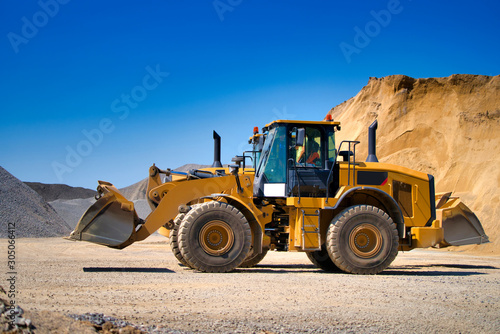 Yellow wheel skid-steer loader machine, loading gravel at construction. Worksite outdoor, heavy equipment machinery. Construction and renovation concept