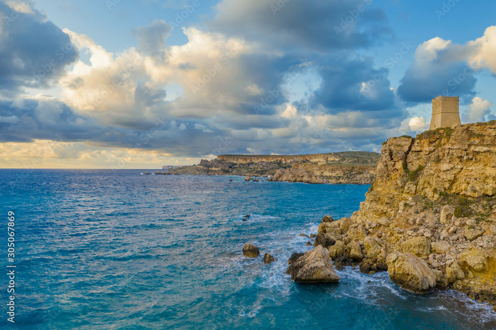 Ghajn Tuffieha Tower. Aerial view from the sea, sunset, cloudy blue sky. Malta country