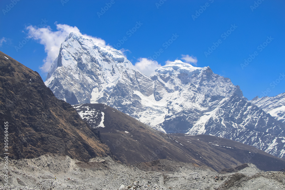 View towards summits of Cholatse and Taboche mountains in Himalayas in Sagarmatha national park in Nepal. Mountain peaks rises above Ngozumpa glacier covered with stones. Route to Everest base camp.