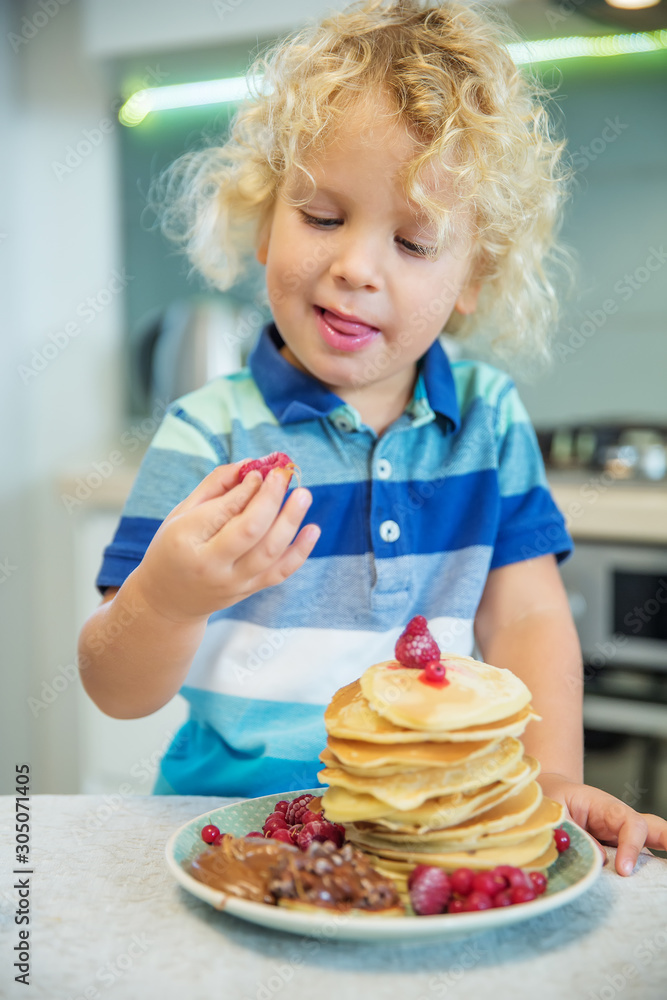 Little curly boy eating sweet pancakes Little curly boy eating sweet pancakes