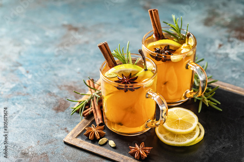 Hot drink cocktail for New Year, Christmas, winter or autumn holidays..Toddy. Mulled pear cider or spiced tea or grog with lemon, pear, cinnamon, anise, cardamom, rosemary.