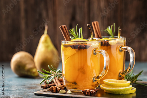 Hot drink cocktail for New Year, Christmas, winter or autumn holidays..Toddy. Mulled pear cider or spiced tea or grog with lemon, pear, cinnamon, anise, cardamom, rosemary.