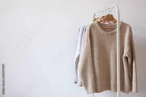 Fotografía Warm sweaters on a wardrobe hanger on a light background
