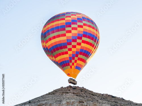 Hot air balloon flying over the hill. Cappadocia tourism activity. © 22Imagesstudio