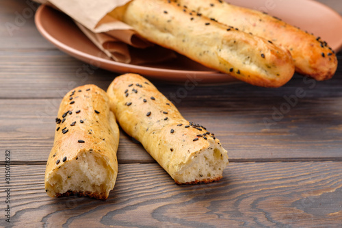 Homemade cheese bread sticks with sesame seeds on a dark wooden background