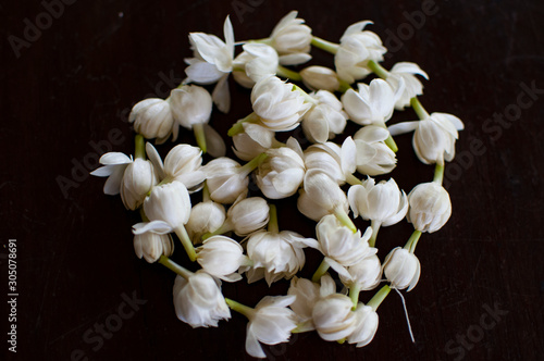 Fragrant jasmine blossom garland wrapped in circle on wooden table traditionally used as an offering to the ghosts and spirits in Thailand.