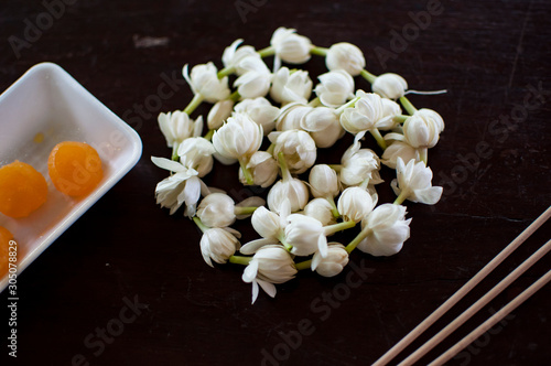 Fragrant jasmine blossom garland wrapped in circle on wooden table traditionally used as an offering to the ghosts and spirits in Thailand.