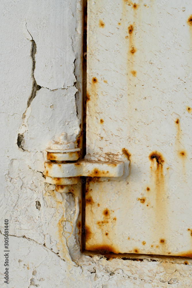 Rusty latch against a rusted white metal wall