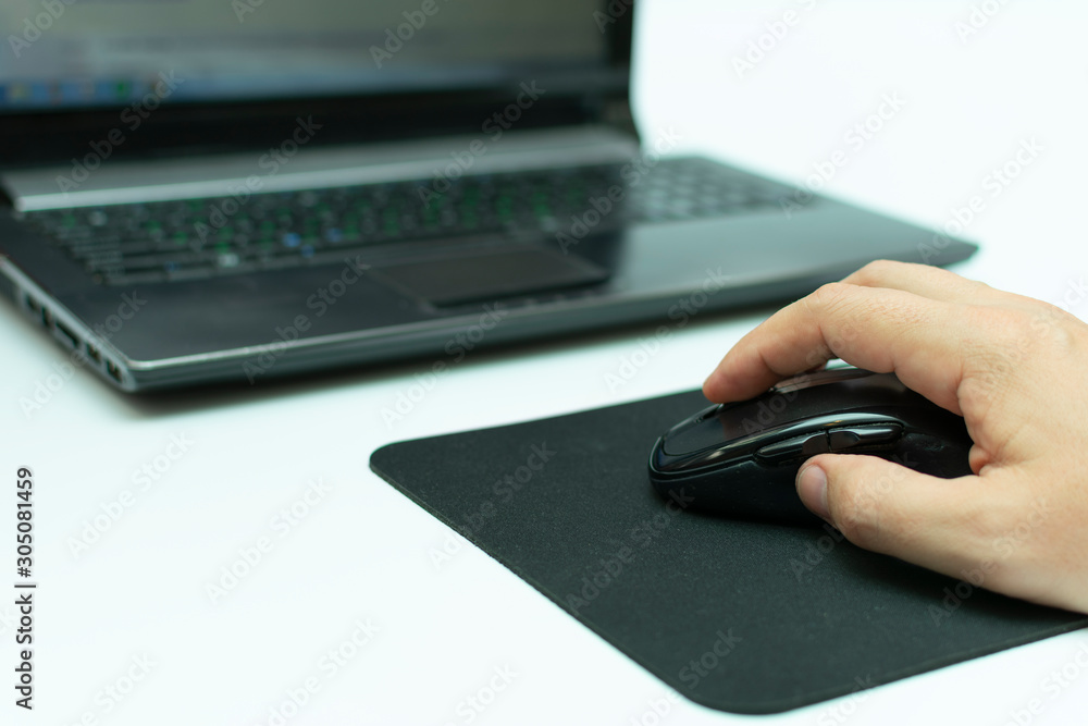 working at a laptop with a wireless computer mouse in hand on a black rug working at a laptop with a wireless computer mouse in hand on a black rug