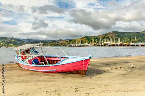 Boat on the beach in Paraty Bay, Rio de Janeiro, Brazil, where passenger boats for tourists to be taken to nearby islands or other villages.