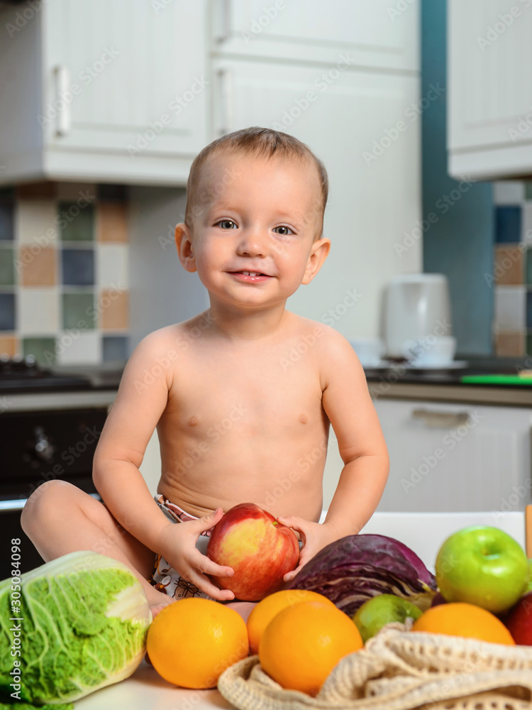 Fototapeta premium Healthy baby boy with apple and fresh vegetables and fruits. Healthy nutrition for children. Ecologikal lifestyie and vegetarian.