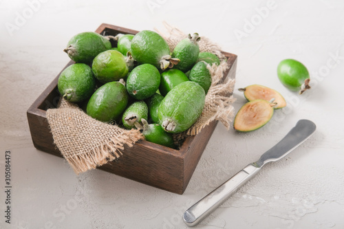 Feijoa fruit in a wooden plate on a cutting kitchen board.