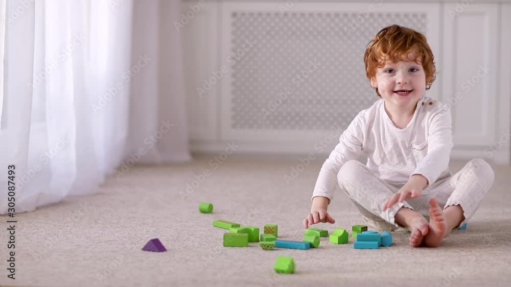 happy toddler kid, boy playing with colorful wooden blocks on the carpet at home happy toddler kid, boy playing with colorful wooden blocks on the carpet at home