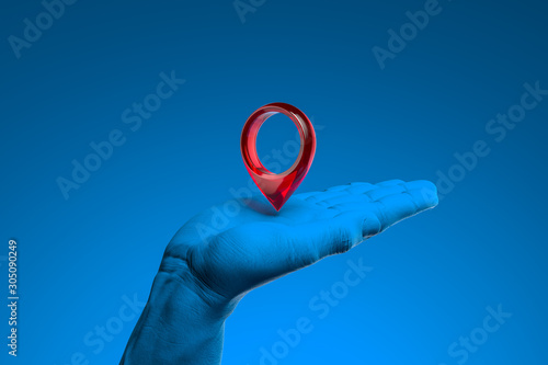 Realistic blue human hand holding red map pin geotag isolated on blue background. 3d rendering photo