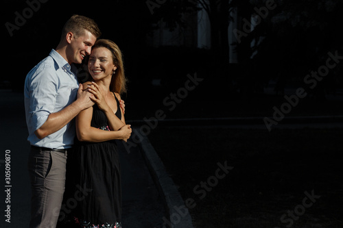 happy, loving couple hugging. guy kisses a girl and hugs from behind, protecting. smiles