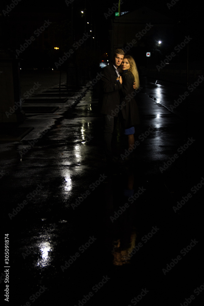 couple in love embracing against a dark background, night, rain, buildings in the city, a park, smiling, attraction. the guy hug the girl. Valentine's Day