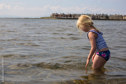 Young girl in the water off a beach on the coast of Scotland.