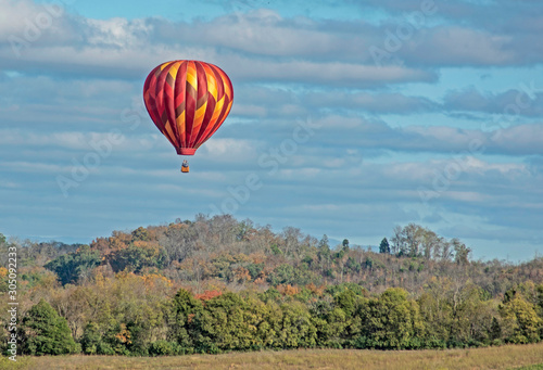 Hot air balloon floats through the sky across the countryside.