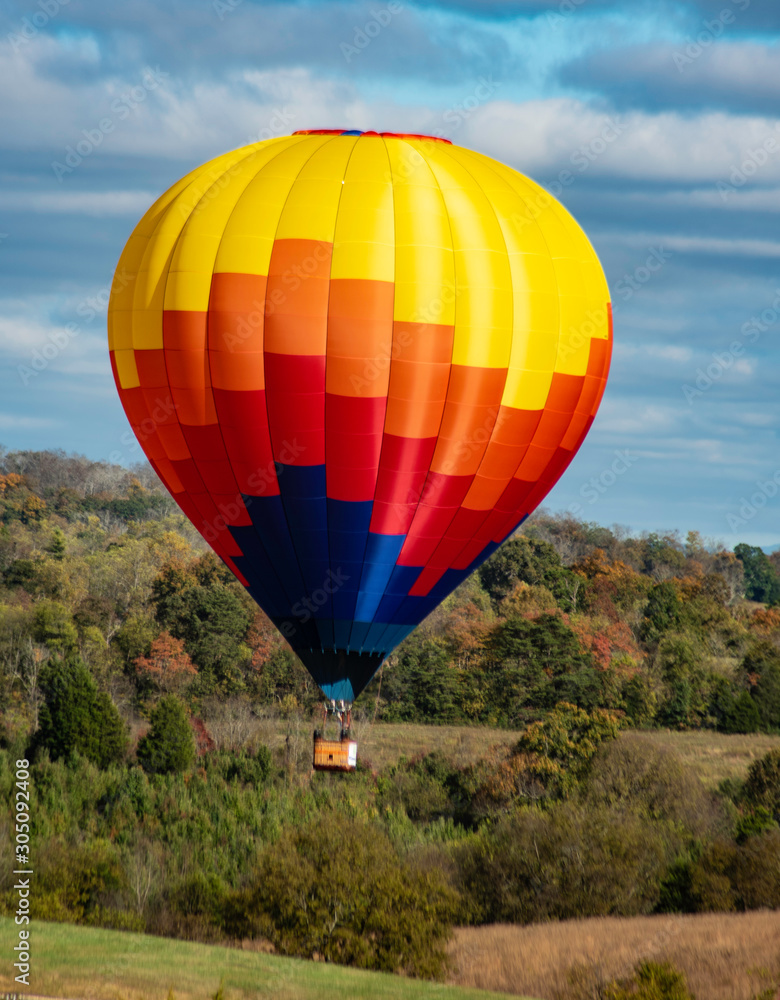 Naklejka premium Hot air balloon floats through the sky across the countryside.