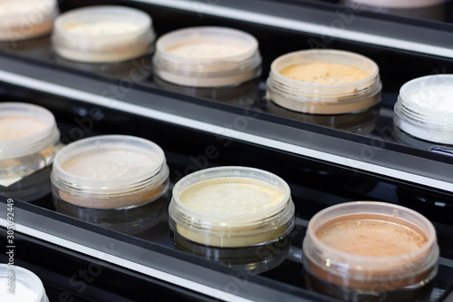 A lot of jars with multi-colored shimmering powder in open black boxes. Close-up