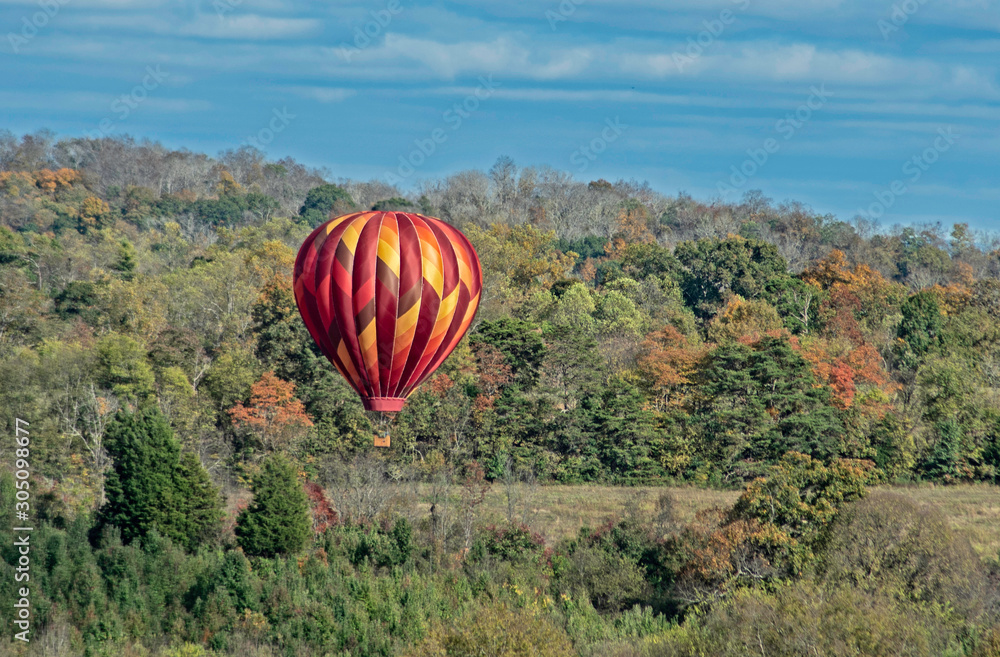 Obraz premium Hot air balloon floats through the sky across the countryside.