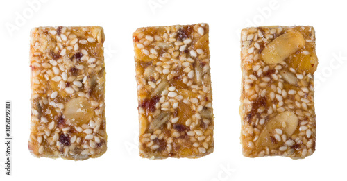 Three sweet shortcrust biscuits glazed by honey coating isolated on white background. Set of yummy rectangular Xmas cookies full of sliced almonds, dried fruits, sesame and sunflower seeds or raisins.
