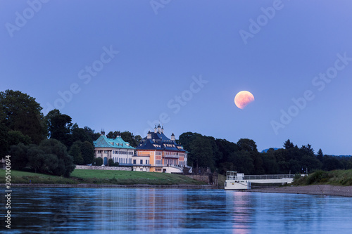Partial lunar eclipse during moonrise over Pillnitz castle in Dresden, Germany