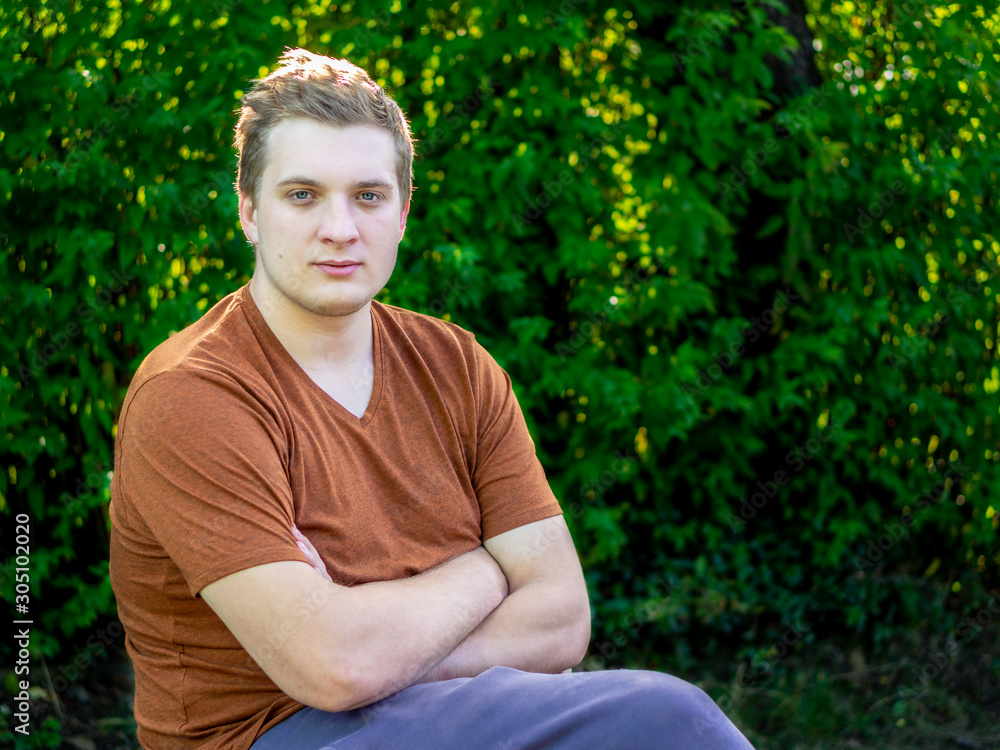 Fototapeta premium A young guy walks in a city Park, sits on a bench