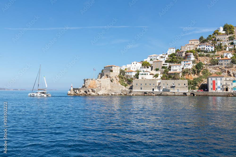 Houses and buildings in the mountains with trees and vegetation and boat in Hydra Island