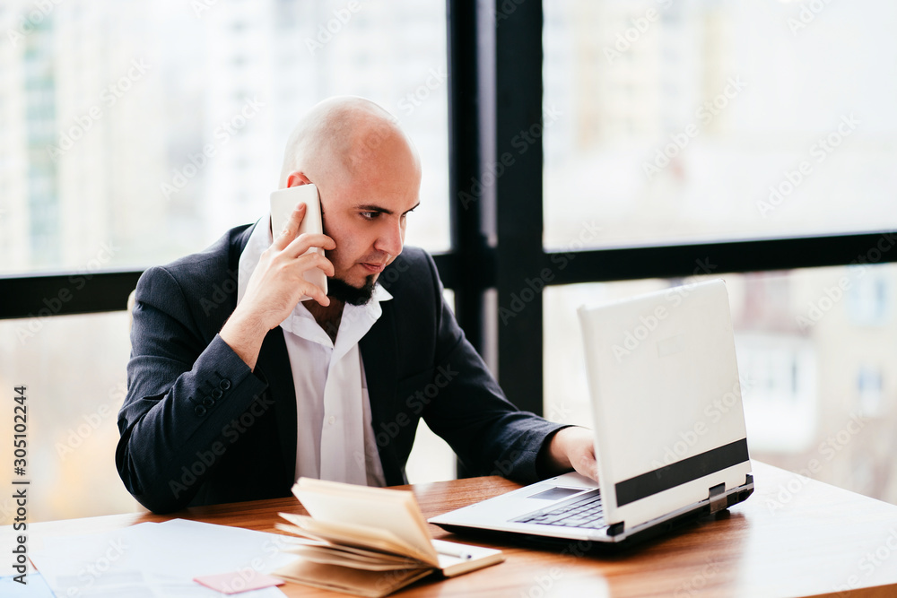 Computer technology and business. Online communication, customer support. Young businessman talking on smartphone at office